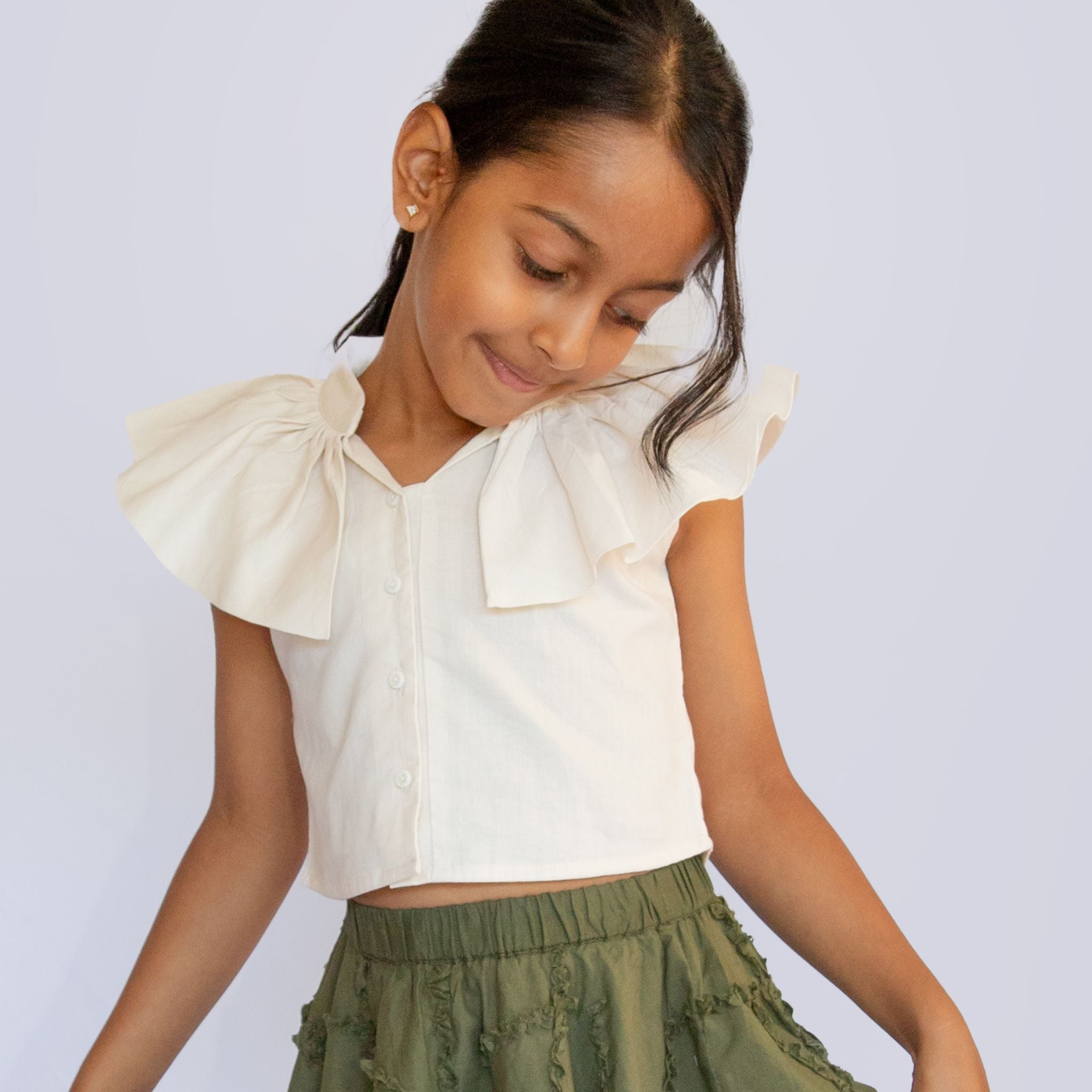 Girl wearing cream cotton sleeveless crop top with frill and front button opening