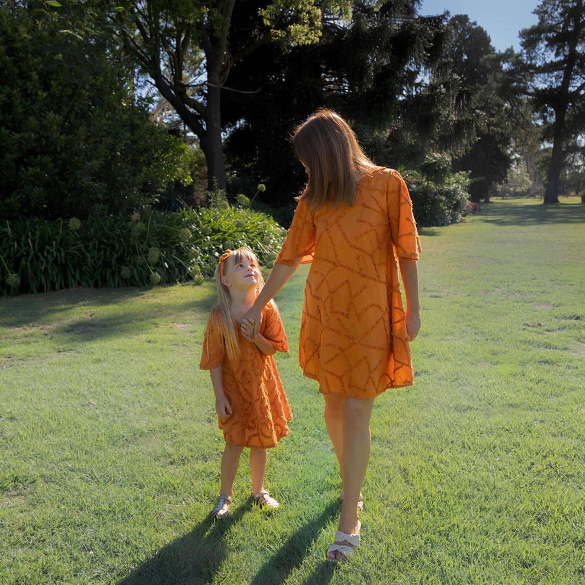 Mother daugther wearing matching cotton textured dress outdoors