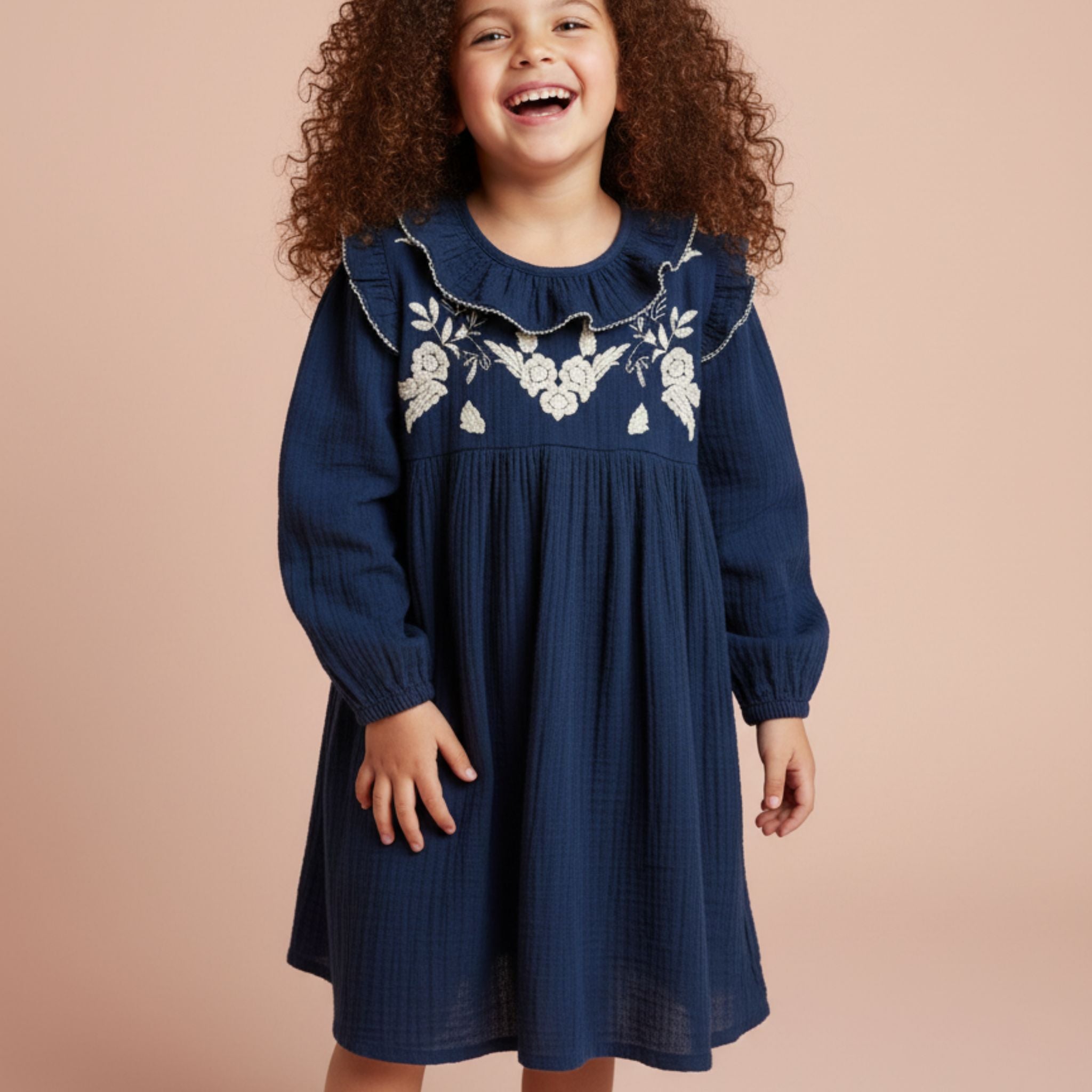 Child wearing a cotton navy blue dress with floral embroidery in front. 